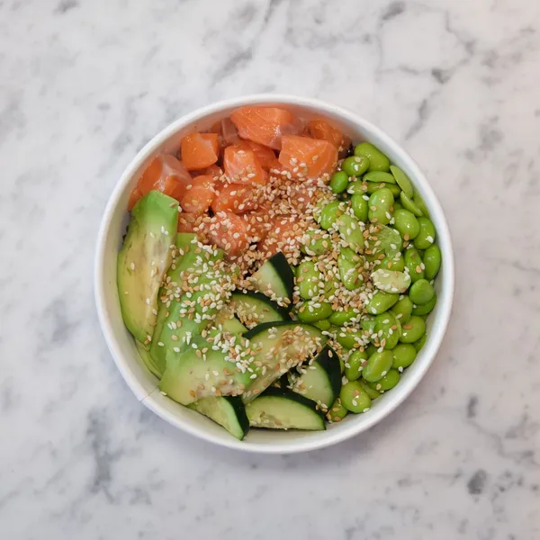 Salmon poke bowl with edamame, cucumber and avocado in a white bowl